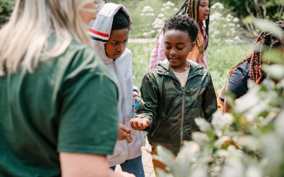 Two student holding out their hands in a nature setting.